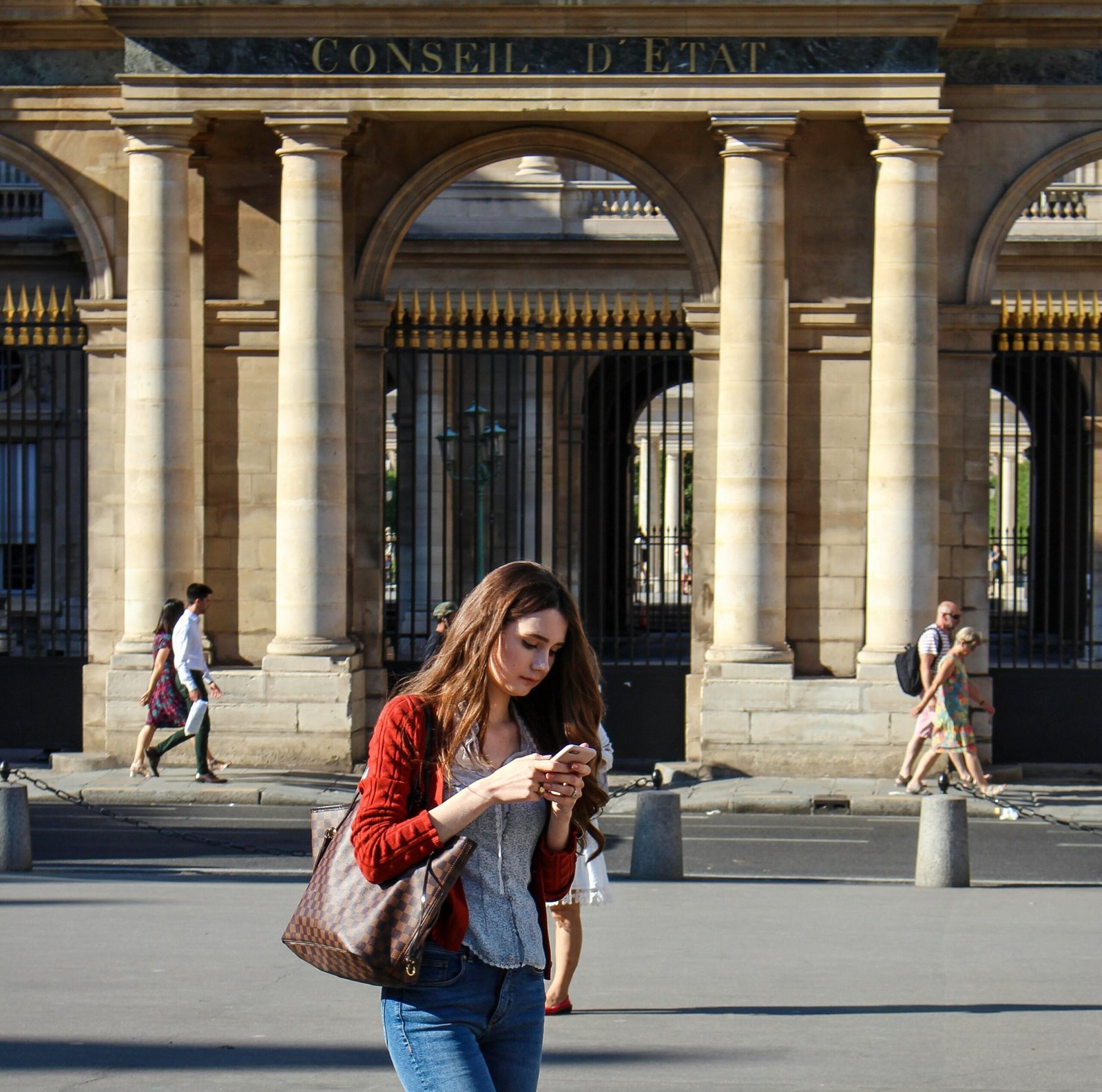 woman in red and black long sleeve shirt standing on sidewalk during daytime
